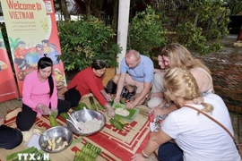 Иностранные гости пробуют делать баньтэт (цилиндрические клейкие рисовые пироги). (Фото: ВИА)