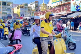 Туристы знакомятся с Хошимином, путешествуя на скутере Vespa. (Фото: ВИА) 