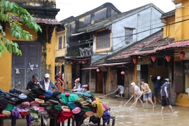 Жители очищают грязь на перекрёстке улиц Нгуен Тхай Хок и Ле Лой в квартале Хойан. (Фото: ВИА)