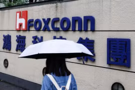 Женщина с зонтиком проходит мимо логотипа Foxconn у здания компании в Тайбэе, Тайвань, 31 октября 2022 года. (Фото: Reuters)