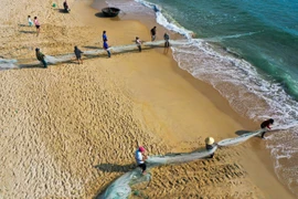 Рыбак медленно тянет рыболовную сеть на берегу. (Фото: ВИА)