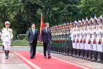 Президент государства Лыонг Кыонг (слева) и президент Франции Эммануэль Макрон обходят строй почетного караула Вьетнамской народной армии. (Фото: ВИA)