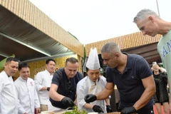 Иностранные туристы пробуют приготовить салат из сырой рыбы на фестивале "Da Nang Food Tour 2025"