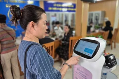 Жители испытывают робота с ИИ для поддержки в выполнении административных процедур в районе Куанам, город Ханой (Фото: ВИА )