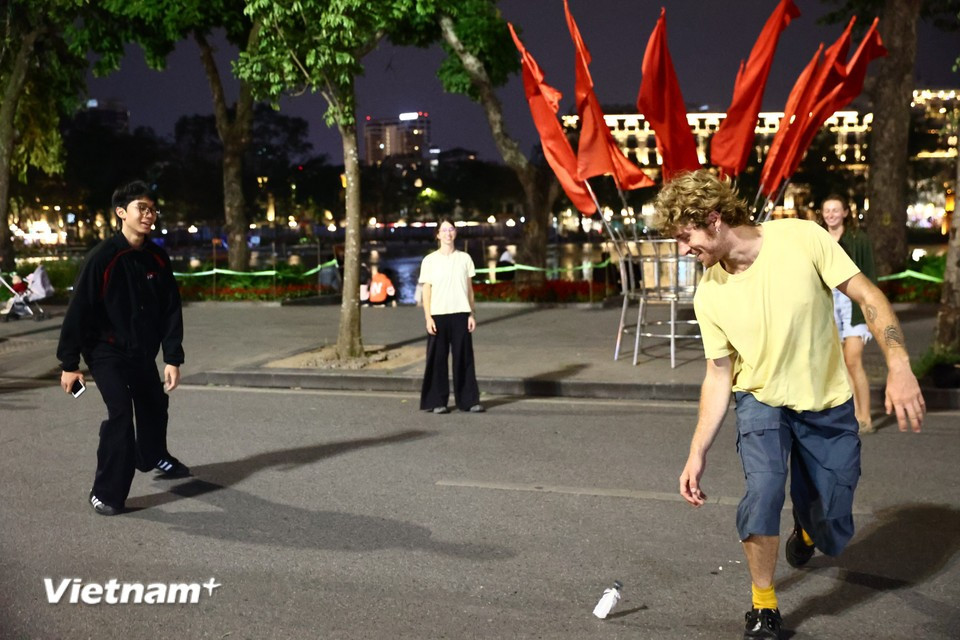 Группа иностранцев играет в дакау — традиционную игру с воланом, популярную у озера Хоанкием, — и радушно приглашает прохожих присоединиться. Фото: Vietnam+.