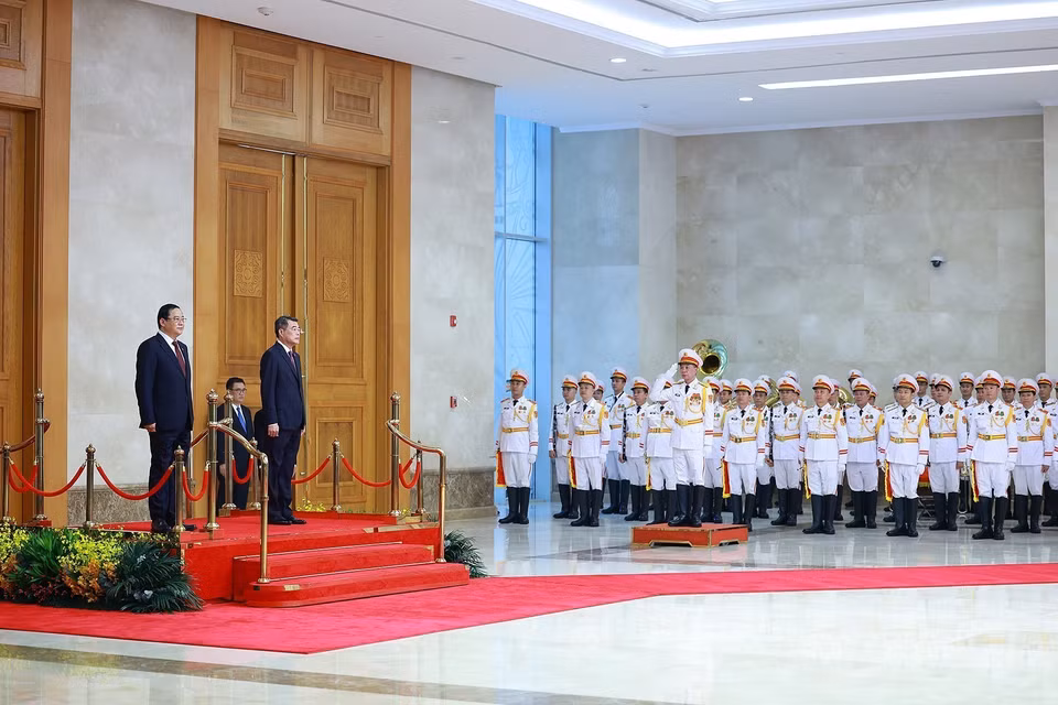 Премьер-министр Ле Минь Хынг и Премьер-министр Лаоса Сонексай Сипхандон слушают исполнение государственных гимнов двух стран военным оркестром. Фото: ВИА.