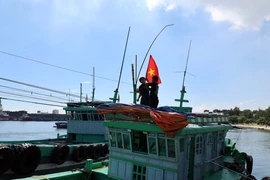 Сотрудники и военнослужащие пограничной станции Шонча (Командование пограничных войск города Дананг) вручают Государственный флаг рыболовному судну рыбаков. (Фото: ВИА)