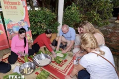 Иностранные гости пробуют делать баньтэт (цилиндрические клейкие рисовые пироги). (Фото: ВИА)