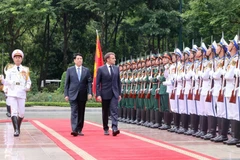 Президент государства Лыонг Кыонг (слева) и президент Франции Эммануэль Макрон обходят строй почетного караула Вьетнамской народной армии. (Фото: ВИA)