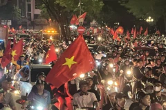  Люди выходят на улицы Ханоя, размахивая национальным флагом в знак празднования победы. (Фото: ВИA) 