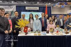 Посол Фам Винь Куанг (седьмой слева) фотографируется на память с сотрудниками Посольства у стенда Вьетнама на выставке. (Фото: ВИА)