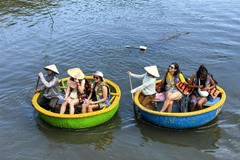 Иностранные туристы пробуют катание на лодке-корзине в кокосовом лесу Камтхань. (Фото: ВИА)