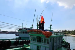 Сотрудники и военнослужащие пограничной станции Шонча (Командование пограничных войск города Дананг) вручают Государственный флаг рыболовному судну рыбаков. (Фото: ВИА)