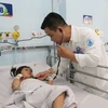 Врач Зы Туан Куи, заведующий отделением инфекционных и неврологических заболеваний Детской больницы №1 города Хошимин, осматривает ребёнка, больного энтеровирусной инфекцией «рука-нога-рот». Фото: ВИА.