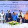 Генеральный директор компании KN Vientiane Group Co., Ltd Ле Хюи Хоанг и директор компании Real Concept Real Estate Sole Co., Ltd Буавиенг Чампафан подписывают документы о сотрудничестве в присутствии участников церемонии. Фото: ВИА