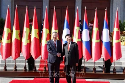 Генеральный секретарь, Президент Лаоса Тхонглун Сисулит приветствует Генерального секретаря То Лама. (Фото: ВИА).