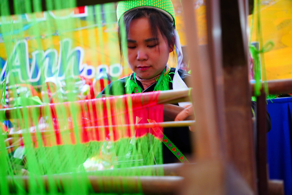 Женщина в национальном костюме народности Нунг демонстрирует традиционную технику ткачества на стенде провинции Лангшон (Фото: Ты Бить Нгок)