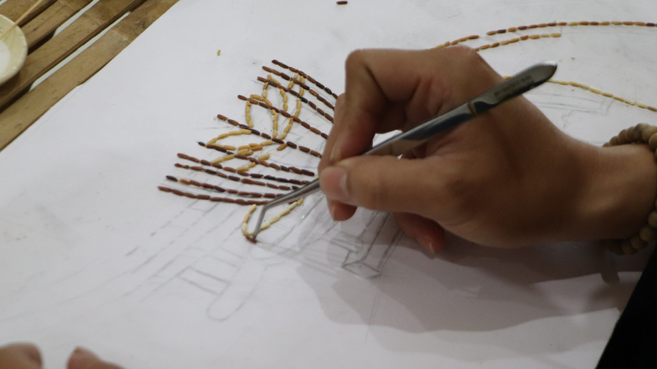 Кхыу Тан Быу работает над созданием картины из риса (Фото: ВИА)