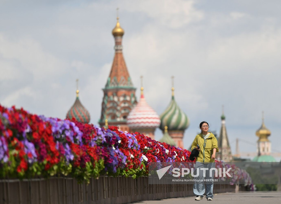 Молодая женщина идёт по мосту, украшенному цветами в рамках фестиваля «Сады и Цветы» в Москве (Фото: Спутник)