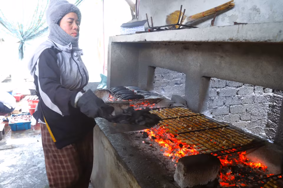 Подсыпка древесного угля в печи для поддержания ровного и устойчивого огня, способствующего быстрому приготовлению рыбы (Фото: ВИА)