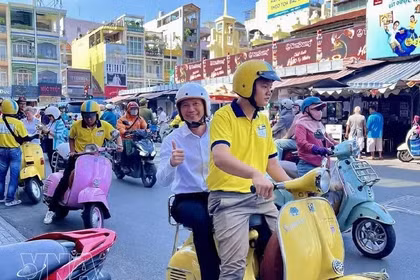 Туристы знакомятся с Хошимином, путешествуя на скутере Vespa. (Фото: ВИА) 