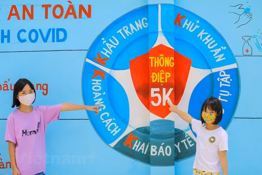 Дети позируют рядом с картинкой о 5К-сообщении Минздрава. (Фото: Vietnam +)