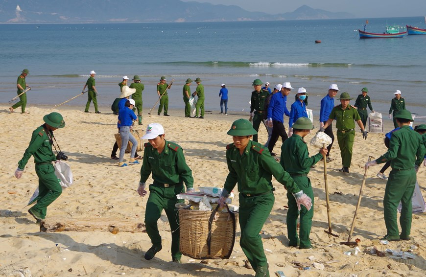 Члены Молодежного союза Биньдинь объединяют усилия для очистки пляжа Ньонли. (Фото: Куок Зунг / ВИА)