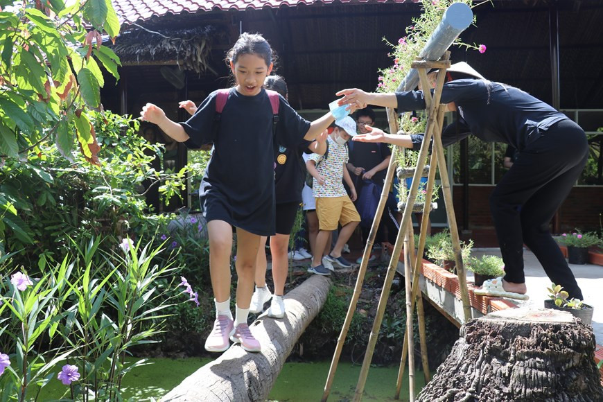 Юные туристы переходят по кокосовому мосту на сырьевой какао-плантации Alluvia Chocolatier. (Фото: ВИА)