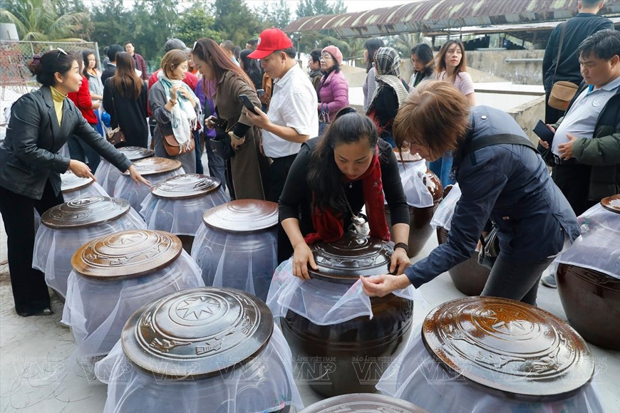 Туристы в цеху по производству соуса из моллюсков в Кондене. (Фото: VNP/ВИА)