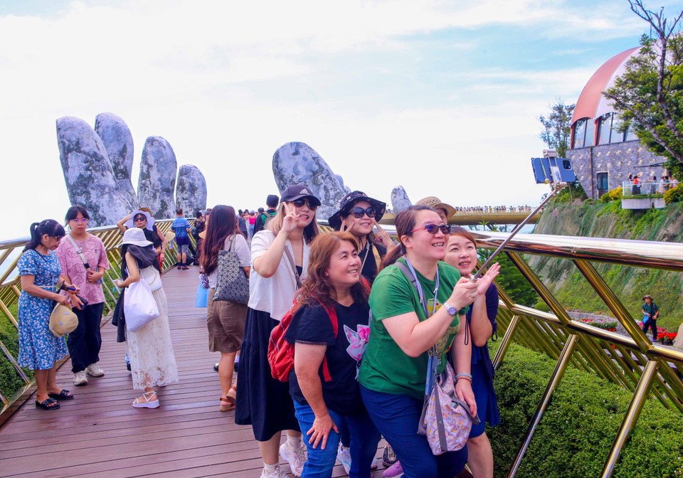 Иностранные туристы делают фото на Золотом мосту в туристической зоне Sun World Ba Na Hills. (Фото: ВИА)