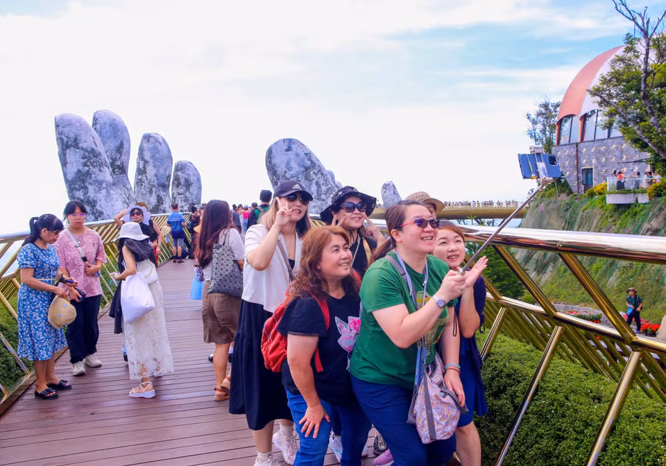 Иностранные туристы делают фото на Золотом мосту в туристической зоне Sun World Ba Na Hills. (Фото: ВИА)
