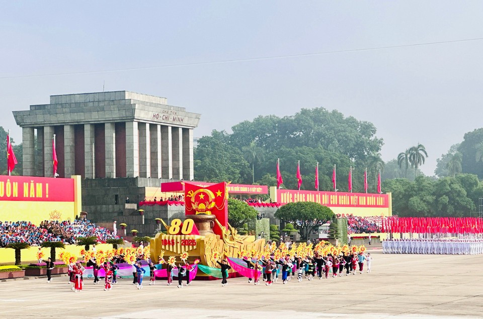 Впереди колонны, входящей на площадь Ба Динь, движется автомобиль с макетом Государственного герба Социалистической Республики Вьетнам. Корпус машины оформлен орнаментом «Гребля на лодке», связанным с бронзовыми барабанами Донгшон — символом духа великого национального единства. (Фото: Vietnam+)