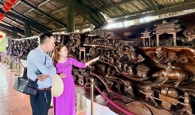 Туристы осматривают гигантское панно из корневой древесины длиной почти 25 м и весом около 20 тонн, которое считается одним из самых сложных и впечатляющих произведений такого рода во Вьетнаме (Фото: ВИА)