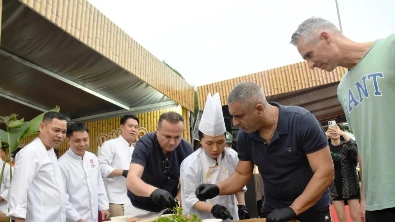 Иностранные туристы пробуют приготовить салат из сырой рыбы на фестивале "Da Nang Food Tour 2025"