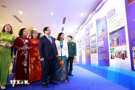Премьер-министр Фам Минь Тьинь осматривает экспозицию, посвящённую развитию проекта «Поддержка женского предпринимательства в период 2017–2025 годов». Фото: ВИА.