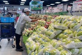 Сотрудник супермаркета Lotte Mart раскладывает фруктовую продукцию. Фото: ВИА.