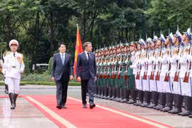 Президент государства Лыонг Кыонг (слева) и президент Франции Эммануэль Макрон обходят строй почетного караула Вьетнамской народной армии. (Фото: ВИA)
