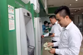 Офисные работники снимают деньги в банкомате. (Фото: ВИА)
