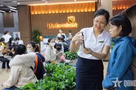Сотрудник Вьетнамского внешнеторгового коммерческого банка (Vietcombank) помогает клиенту пройти процедуру биометрической идентификации. (Фото: qdnd.vn)