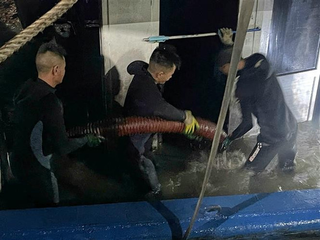Силы спасения осуществляют откачку воды из судна перед началом буксировки. Фото: ВИА. vna-potal-vu-lat-tau-tren-vinh-ha-long-truc-vot-thanh-cong-va-lai-dat-tau-ve-bo-8159125.jpg
