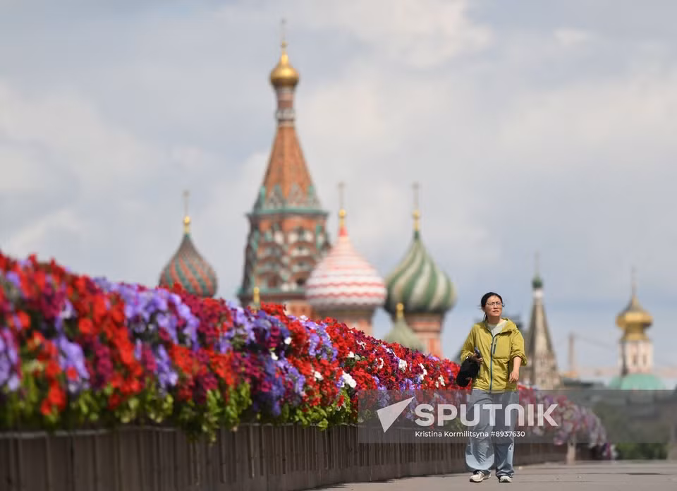 Молодая женщина идёт по мосту, украшенному цветами в рамках фестиваля «Сады и Цветы» в Москве (Фото: Спутник)