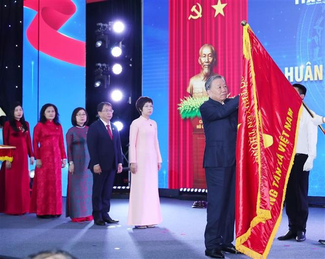Генеральный секретарь То Лам прикрепляет орден Хо Ши Мина к Традиционному знамени ВИА. Фото: ВИА.