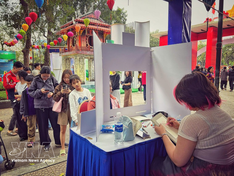 Посетители участвуют в бесплатном рисовании портретов на мероприятии. Фото: Vietnam+.