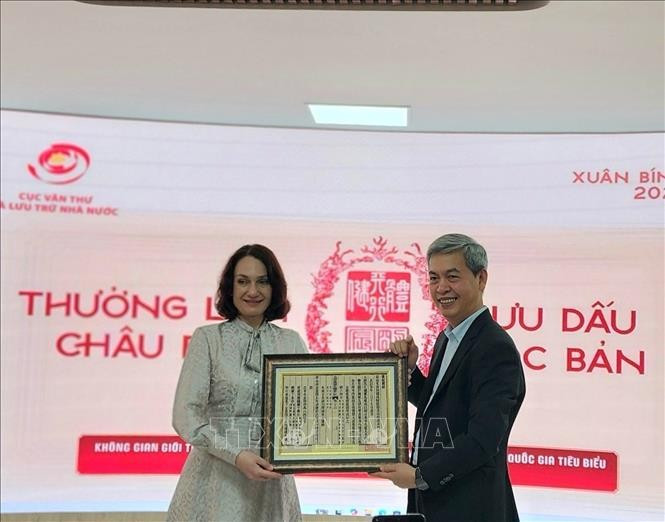 Директор Государственного управления делопроизводства и архивов Данг Тхань Тунг вручает госпоже Елене Бездетко, супруге Посла России во Вьетнаме, оттиск с ксилографической доски с государственным наименованием Вьетнама. Фото: ВИА.