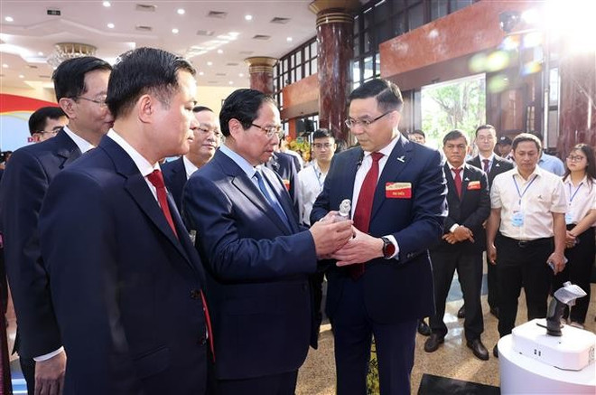 Премьер-министр Фам Минь Тьинь слушает представление типичных продуктов Petrovietnam (Фото: ВИА) vna-potal-thu-tuong-du-dai-hoi-dang-bo-tap-doan-cong-nghiep-nang-luong-quoc-gia-viet-nam-8187430.jpg