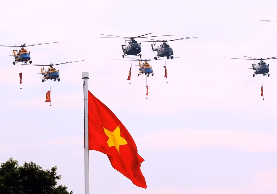 Группа вертолетов Ми-171, Ми-17 и Ми-8 с партийным и государственным флагами пролетает над площадью Бадинь. (Фото: ВИA)