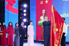 Генеральный секретарь То Лам прикрепляет орден Хо Ши Мина к Традиционному знамени ВИА. Фото: ВИА.