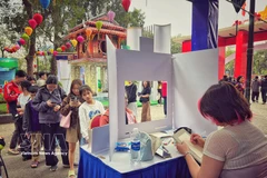 Посетители участвуют в бесплатном рисовании портретов на мероприятии. Фото: Vietnam+.