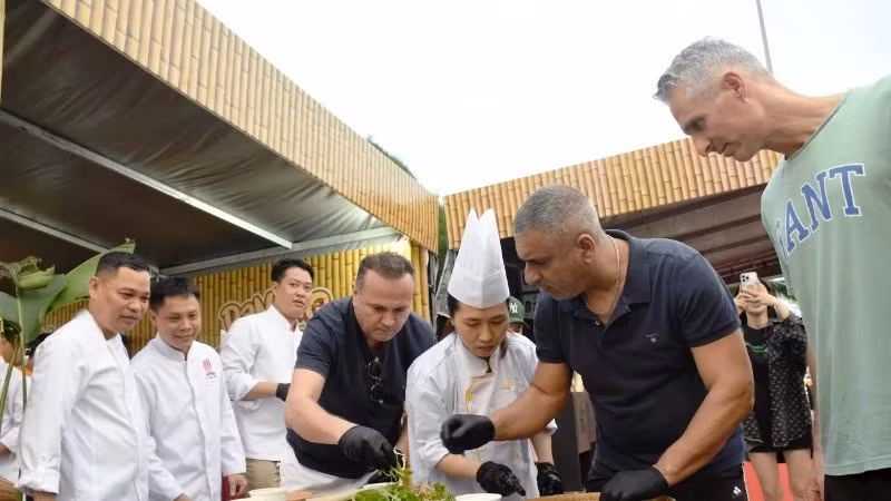 Иностранные туристы пробуют приготовить салат из сырой рыбы на фестивале "Da Nang Food Tour 2025"