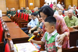 Заместитель Председателя НС Нгуен Тхи Тхань вручает подарки и показывает учащимся начальной школы, как пользоваться электронной ручкой для изучения английского языка (Фото: ВИА)